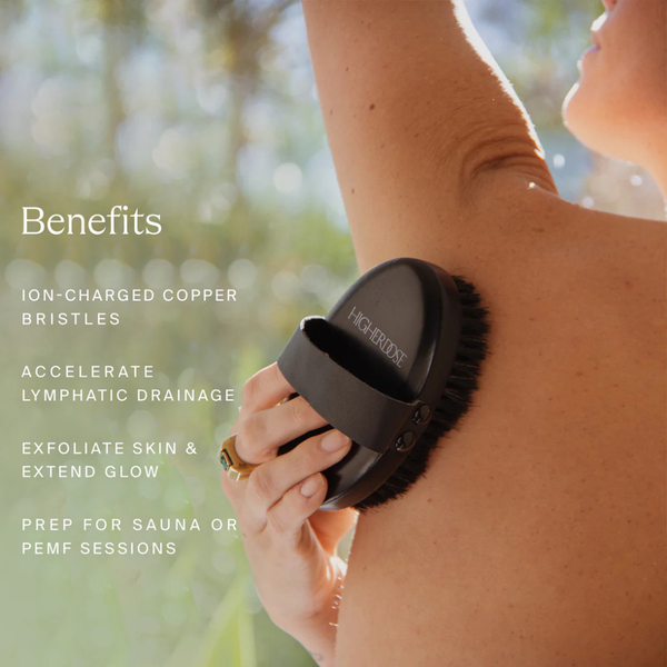 Mujer usando el cepillo corporal de cobre HigherDOSE Supercharge en el brazo para activar el drenaje linfático
