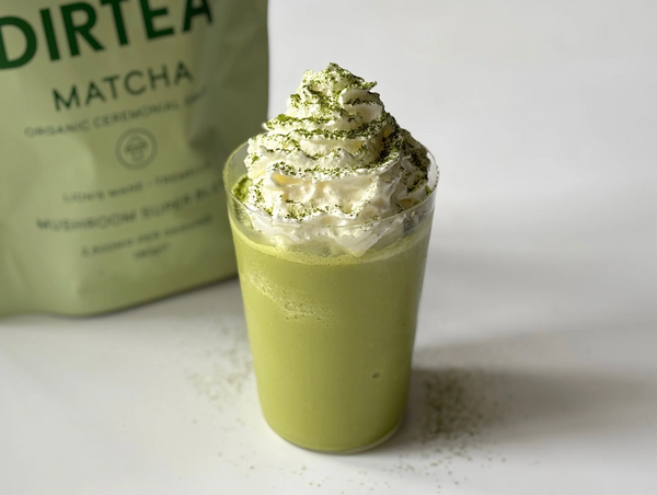 Matcha latte helado Dirtea con crema batida, servido en vaso transparente.