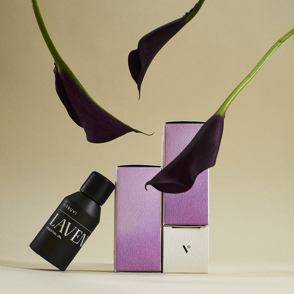 Botella de aceite esencial de lavanda Vitruvi con flores moradas, ideal para relajación y difusor.